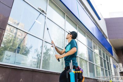 ensterputzer-mit-sonnen-brillen-beim-fensterputzen-mit-stange
