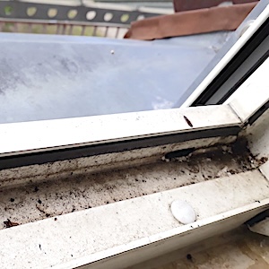 Ein-offenes-Fenster-zeigt-verschmutzte-Fensterfuehrungen.